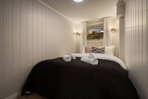 A hotel room with a bed, pillows, and a window with curtains. - Sydpol Designer Home Classic Apartment (Tromsø)
