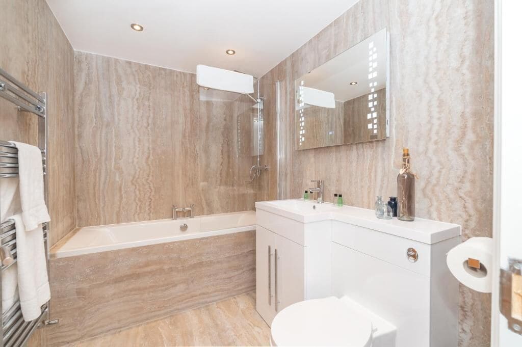 A modern bathroom with a bathtub, a toilet, and a vanity with a mirror.
