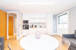 A modern kitchen with white cabinets, a microwave, and a coffee maker. - Hyde Park Premium Apartments (London)