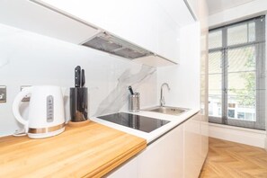 A modern kitchen with a built-in stove, a kettle, and a knife block. - Hyde Park Premium Apartments (London)