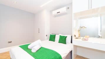 Una habitación de hotel con una cama, ropa de cama verde y blanca, una lámpara de noche y una mesita de noche pequeña con una lámpara y algunos objetos.