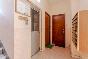 A hallway with a wooden door, a metal intercom, a notice board, and a tiled floor. - A bright and comfortable 48 square meters apartment, perfect for three people, located on the third floor of a renovated building with an elevator (NOT accessible to people with disabilities).The property is situated in an extremely quiet area well-serve (Turin)