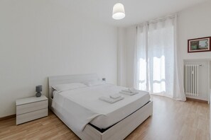 Ein schlicht eingerichtetes Schlafzimmer mit einem Einzelbett, Nachttisch und Heizkörper.