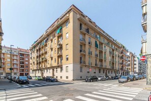 A multi-story residential building with balconies, a crosswalk, and parked cars. - A bright and comfortable 48 square meters apartment, perfect for three people, located on the third floor of a renovated building with an elevator (NOT accessible to people with disabilities).The property is situated in an extremely quiet area well-serve (Turin)