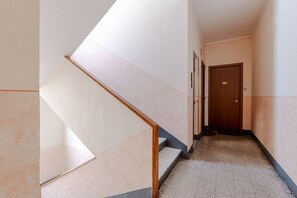 A hallway with a staircase, a door at the end, and a tiled floor. - A bright and comfortable 48 square meters apartment, perfect for three people, located on the third floor of a renovated building with an elevator (NOT accessible to people with disabilities).The property is situated in an extremely quiet area well-serve (Turin)