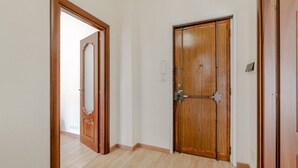 Um corredor com portas de madeira, soalho claro e parede lisa.