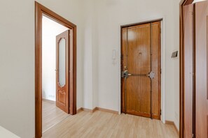 Ein Korridor mit Holztüren, einem hellen Boden und einer schlichten Wand.