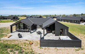 A modern house with a patio area, a hot tub, and a view of the sea. - Nice home in Otterup with WiFi (Otterup)