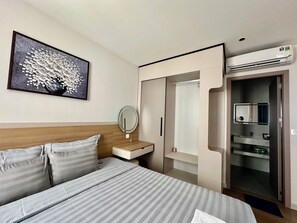 A hotel room with a bed, a bedside table with a mirror, a wardrobe, and an air conditioning unit. - Spacious modern 2BR apartment Phu Quoc (Phu Quoc)