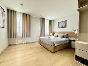 A modern hotel room with a wooden bed, a bedside table, a lamp, and a painting on the wall. - Spacious modern 2BR apartment Phu Quoc (Phu Quoc)