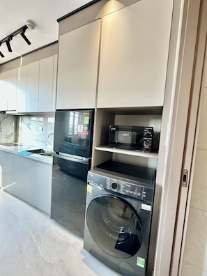 A modern kitchen with built-in appliances, including a washing machine and a microwave. - Spacious modern 2BR apartment Phu Quoc (Phu Quoc)