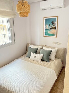 A bedroom with a bed, a window, an air conditioner, a wall-mounted picture, and a wall socket. - Detached 3-Bed Villa with Shared Pool near La Zenia, Orihuela Costa (Orihuela)