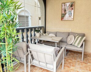 An outdoor seating area with a table and chairs, a potted plant, and a wall-mounted picture. - Detached 3-Bed Villa with Shared Pool near La Zenia, Orihuela Costa (Orihuela)