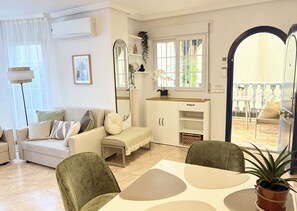 A modern living room with a sofa, chairs, a coffee table, and a dining area. - Detached 3-Bed Villa with Shared Pool near La Zenia, Orihuela Costa (Orihuela)