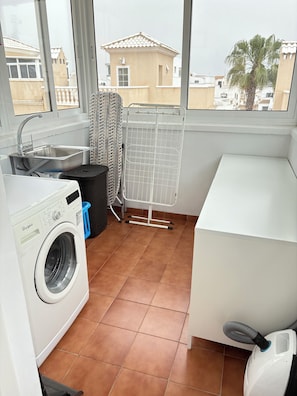 A laundry room with a washing machine, a sink, a drying rack, and a white cabinet. - Detached 3-Bed Villa with Shared Pool near La Zenia, Orihuela Costa (Orihuela)