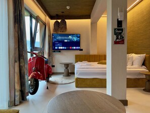 A hotel room with a bed, a red scooter, a television, and a wooden wall. - Apartament Primavera Studio (Zakopane)