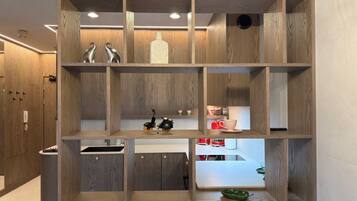 Een moderne keuken met houten kastjes, een ingebouwde vaatwasser en een eethoekje met een rode theepot en kopjes.