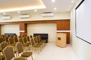 A conference room with rows of chairs, a projector screen, and a television.