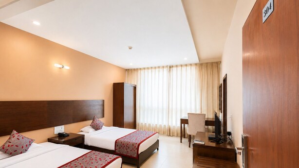 Habitación de hotel con dos camas, un escritorio, una silla, un televisor y un armario.