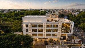Un hotel de varios pisos con un diseño moderno, que cuenta con un patio central y un área de estacionamiento.