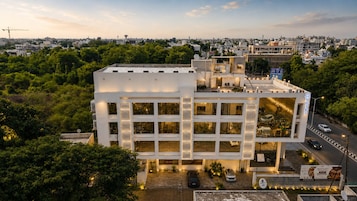 A multi-story hotel with a modern design, featuring a central courtyard and a parking area.