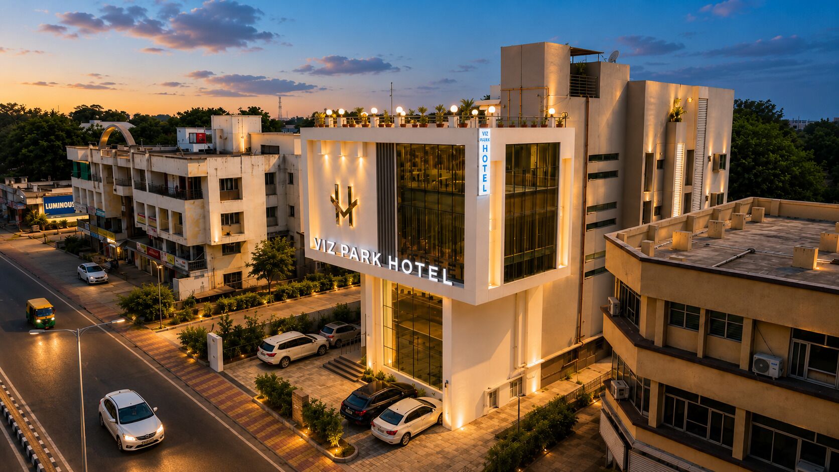 A modern hotel with a prominent sign, multiple parking spaces, and a street view.