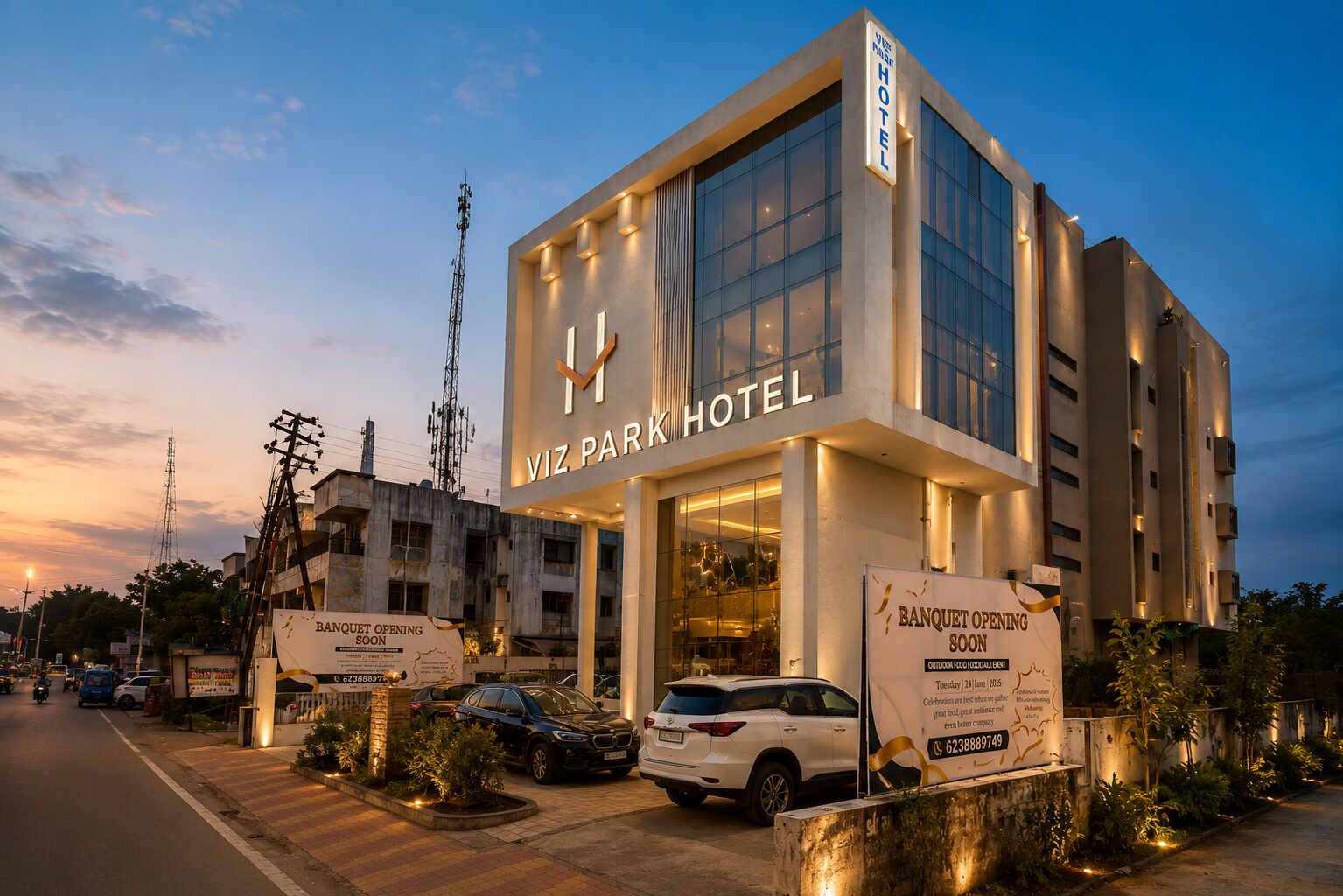 A modern hotel with a large glass facade, signage for a banquet opening, and a parking area with cars.