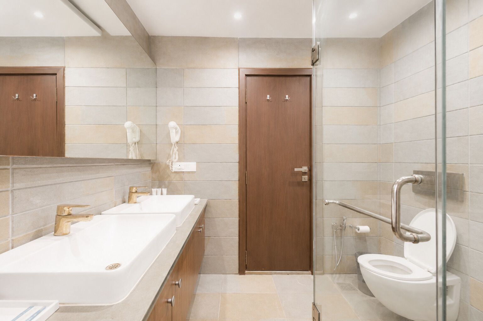 Un baño moderno con ducha, inodoro y dos lavamanos.