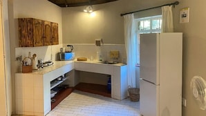 A compact kitchen with white cabinets, a microwave, a sink, and a refrigerator. - Palala River Cottages (Waterberg)