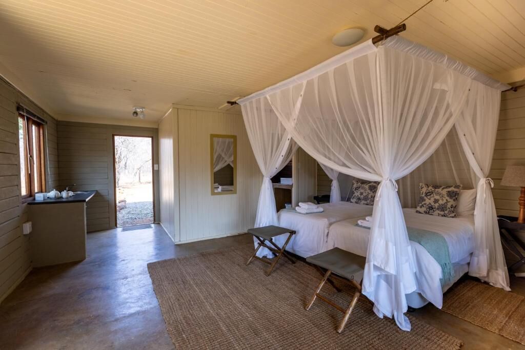 A bedroom with a canopy bed, a small table, and a bench.