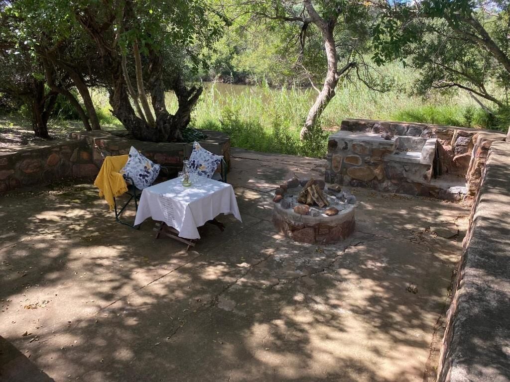 An outdoor seating area with a table and chairs, a fire pit, and a stone wall.