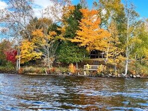 A lakeside view with autumn foliage, a wooden dock, and a house partially obscured by trees. - Panoramic Views, Sunrise/Sunset, EV Charger Kayaks (Magnetawan)