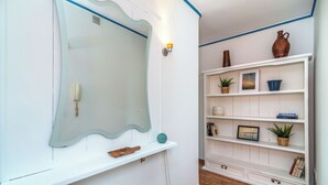 A room with a white wall, a large mirror, a shelf with decorative items, and a wooden floor. - LXR Fuengirola Sun & Beach 2-Bedroom (Fuengirola)