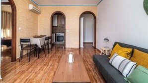 A spacious living area with a wooden coffee table, a sofa with cushions, and a dining area with chairs and a table. - LXR Fuengirola Sun & Beach 2-Bedroom (Fuengirola)
