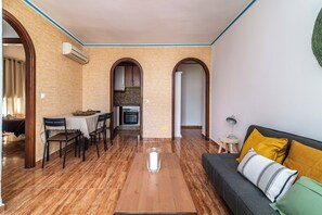 A spacious living area with a wooden coffee table, a sofa with cushions, and a dining area with chairs and a table. - LXR Fuengirola Sun & Beach 2-Bedroom (Fuengirola)