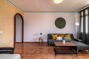 A living room with a sofa, a coffee table, a lamp, and a wall-mounted circular decoration. - LXR Fuengirola Sun & Beach 2-Bedroom (Fuengirola)