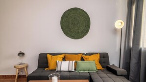 A modern living room with a grey sofa, a wooden coffee table, and a round wall decoration. - LXR Fuengirola Sun & Beach 2-Bedroom (Fuengirola)