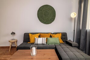 A modern living room with a grey sofa, a wooden coffee table, and a round wall decoration. - LXR Fuengirola Sun & Beach 2-Bedroom (Fuengirola)