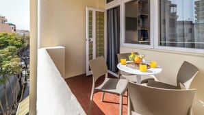 A balcony with a table set for two, chairs, and a window with curtains. - LXR Fuengirola Sun & Beach 2-Bedroom (Fuengirola)
