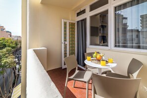 A balcony with a table set for two, chairs, and a window with curtains. - LXR Fuengirola Sun & Beach 2-Bedroom (Fuengirola)
