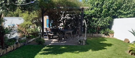 A garden with a wooden pergola, a table, and chairs.