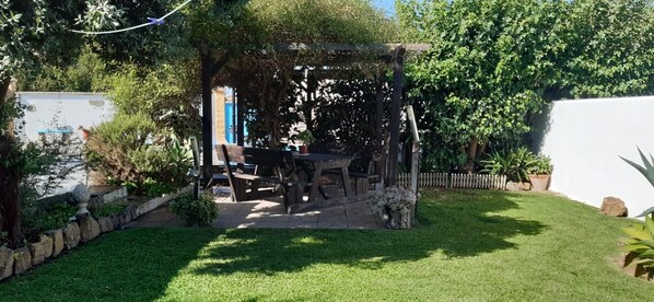 A garden with a wooden pergola, a table, and chairs.