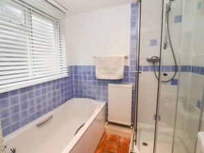 A bathroom with a bathtub, a shower, and a window with blinds. - Cobblers Cottage (Reydon)