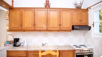 Une cuisine avec des meubles de rangement en bois, une cuisinière, un évier et une chaise.