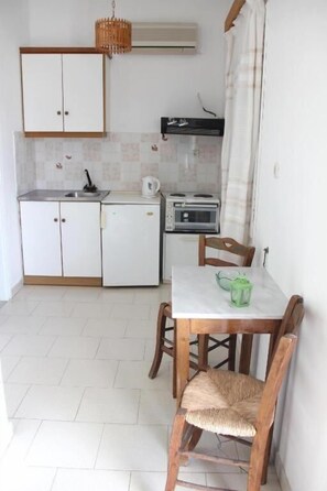 Una cocina compacta con una mesa de comedor, sillas y electrodomésticos básicos.