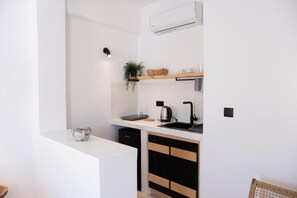 A compact kitchen with a white countertop, black cabinets, and a built-in dishwasher. - Argo Studios (Kini)