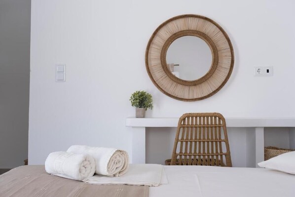 A room with a bed, a round mirror, a wicker chair, and a small potted plant. - Argo Studios (Kini)