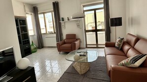 A modern living room with a glass coffee table, leather sofa, and a TV. - Matino Terrace with Ocean View (Matino)