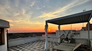 A rooftop terrace with a patterned floor, a covered seating area, and a view of the sunset. - Matino Terrace with Ocean View (Matino)