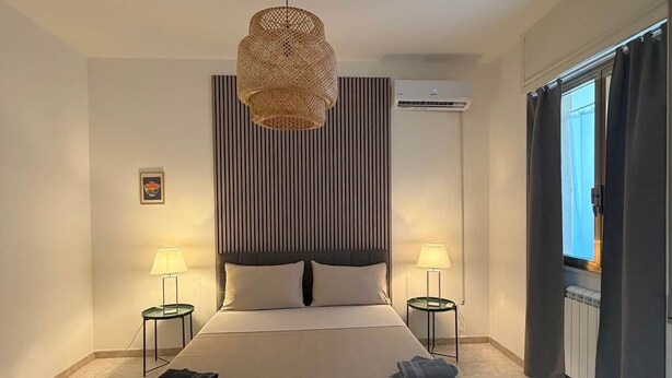 A modern hotel room with a large bed, two bedside tables, a ceiling fan, and an air conditioning unit. - Matino Terrace with Ocean View (Matino)
